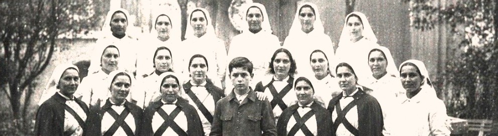 Fotografía antigua de un grupo de enfermeras con toca blanca y, en el centro, un muchacho flaco de rasgos marcados
